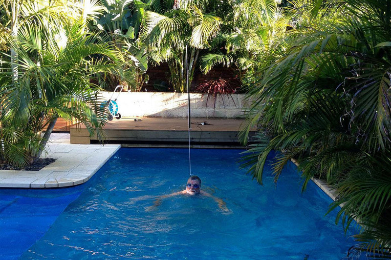 Person swimming in a pool surrounded by tropical plants