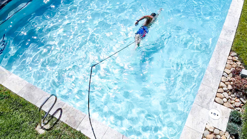 Person swimming with a stationary tether in a pool.